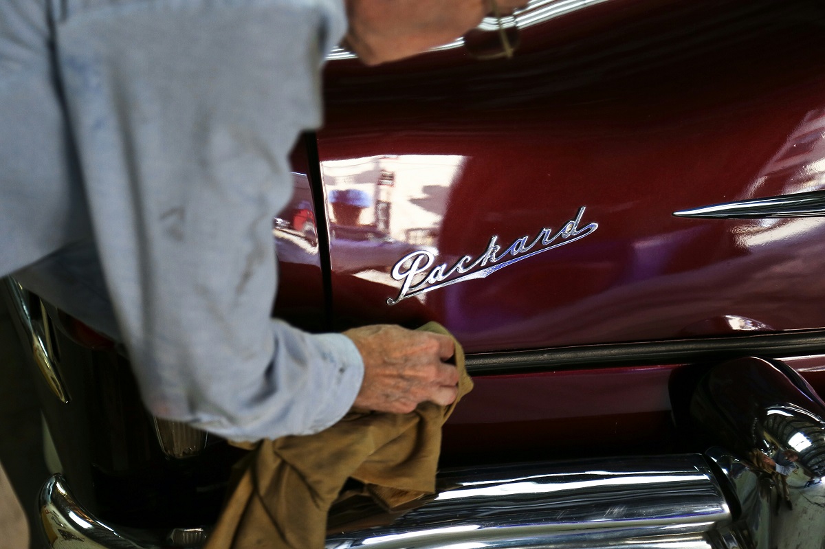 man cleaning a red classic car